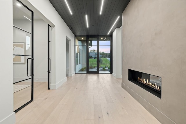 hall featuring light hardwood / wood-style flooring, wooden ceiling, and floor to ceiling windows