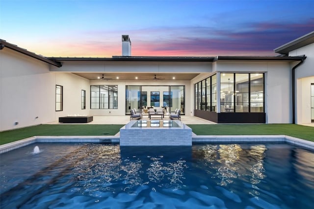 pool at dusk featuring an outdoor living space, a yard, a patio, and ceiling fan