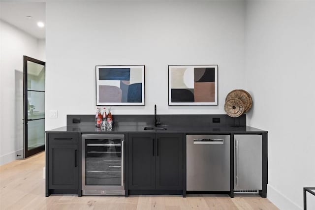 bar featuring sink, light hardwood / wood-style floors, beverage cooler, and dishwasher