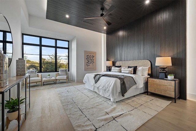 bedroom with ceiling fan, a towering ceiling, and light wood-type flooring