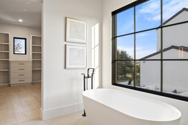 bathroom with a tub to relax in and wood-type flooring