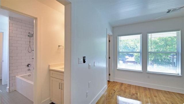 bathroom featuring vanity, tiled shower / bath combo, and wood-type flooring