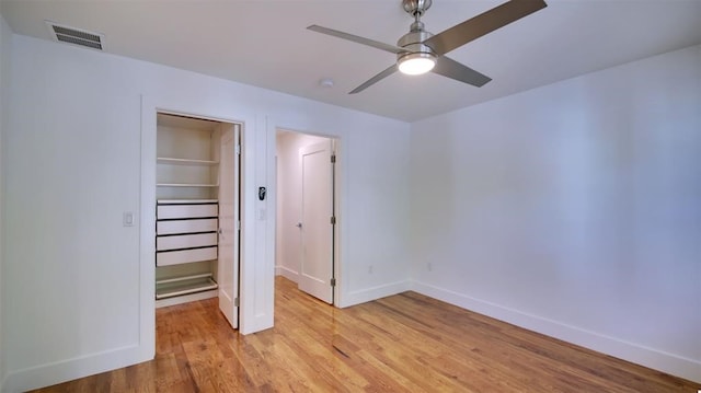 unfurnished bedroom with a closet, a spacious closet, ceiling fan, and light hardwood / wood-style flooring