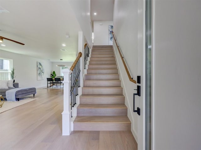 stairway featuring wood-type flooring and ceiling fan