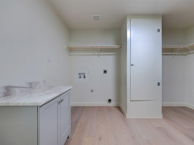 laundry area featuring gas dryer hookup, cabinets, electric dryer hookup, washer hookup, and light hardwood / wood-style floors