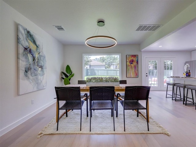 dining space featuring a wealth of natural light, light hardwood / wood-style floors, and french doors