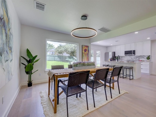 dining space with sink and light hardwood / wood-style flooring