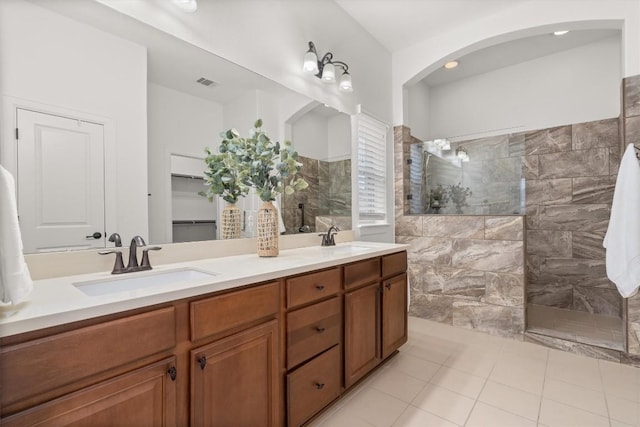 bathroom featuring vanity, tile patterned flooring, and a tile shower