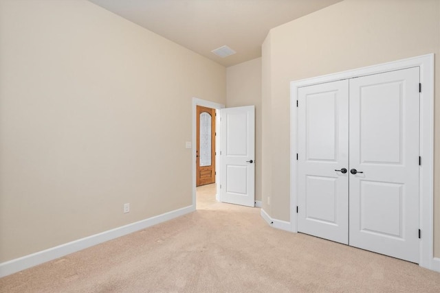 unfurnished bedroom with light carpet and a closet