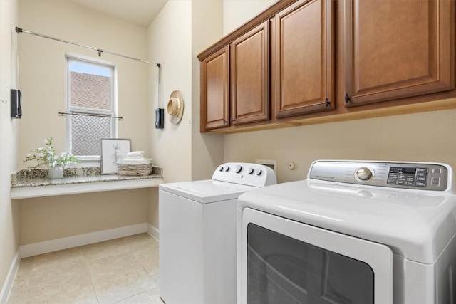 washroom featuring cabinets, washing machine and clothes dryer, and light tile patterned flooring