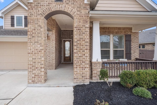 view of exterior entry featuring a garage and covered porch