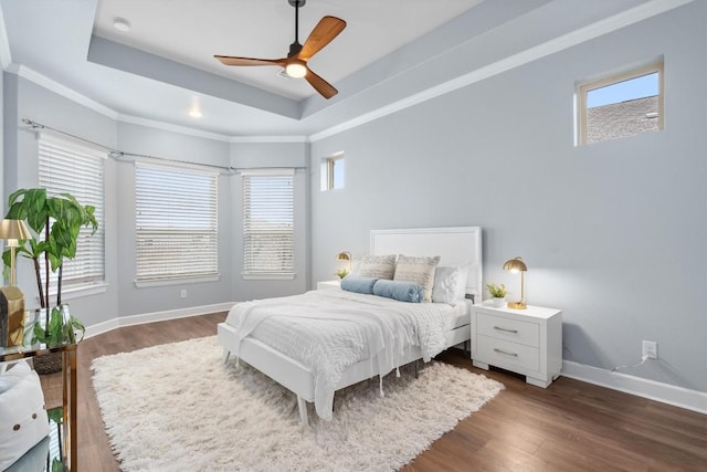 bedroom featuring a tray ceiling, dark hardwood / wood-style flooring, and multiple windows