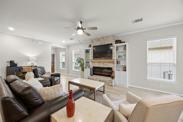 living room with a brick fireplace, ornamental molding, light hardwood / wood-style floors, and ceiling fan