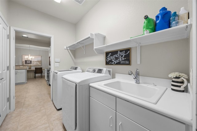 laundry room featuring sink, light tile patterned floors, washer and clothes dryer, an inviting chandelier, and cabinets