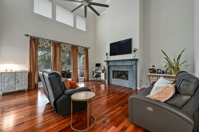 living room featuring ceiling fan, a stone fireplace, a wealth of natural light, and wood-type flooring