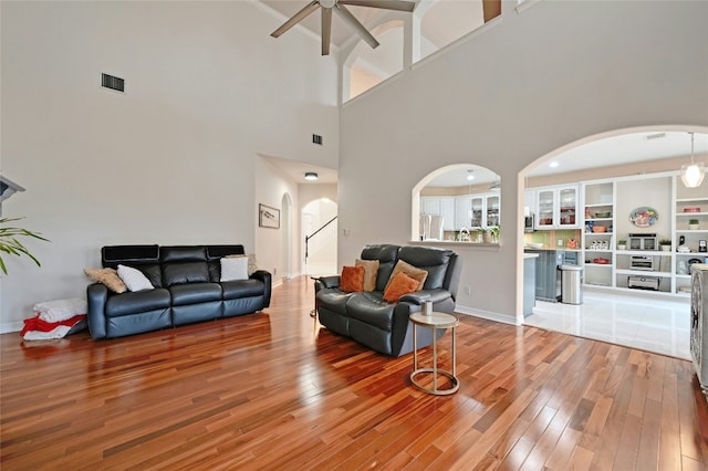 living room with built in shelves, wood-type flooring, and ceiling fan