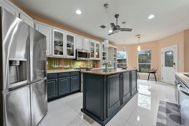 kitchen featuring white cabinetry, decorative light fixtures, appliances with stainless steel finishes, a kitchen island, and backsplash