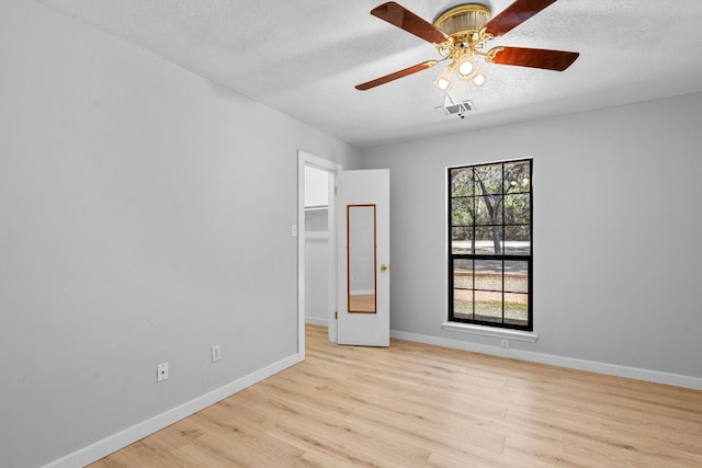 unfurnished room with ceiling fan, plenty of natural light, light hardwood / wood-style floors, and a textured ceiling