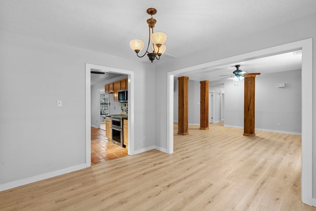 empty room with ceiling fan with notable chandelier, light hardwood / wood-style flooring, and a textured ceiling