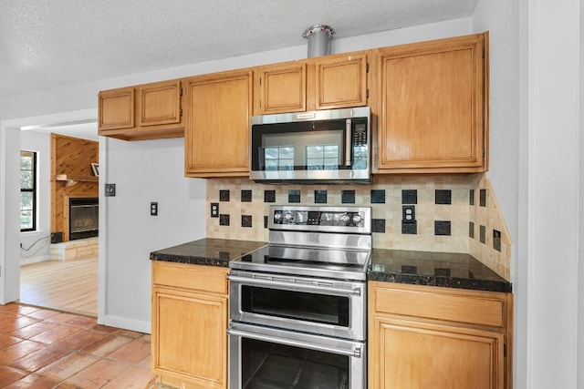 kitchen with tasteful backsplash, a fireplace, stainless steel appliances, and a textured ceiling