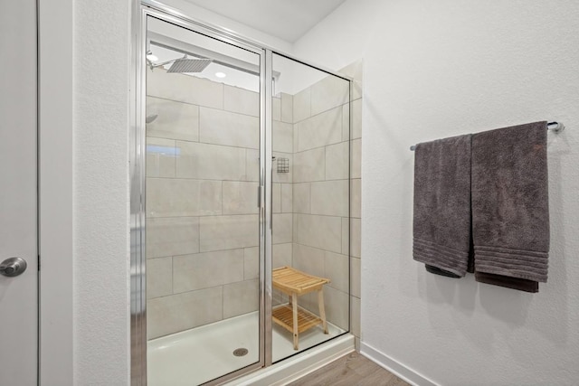 bathroom with hardwood / wood-style flooring and a shower with shower door