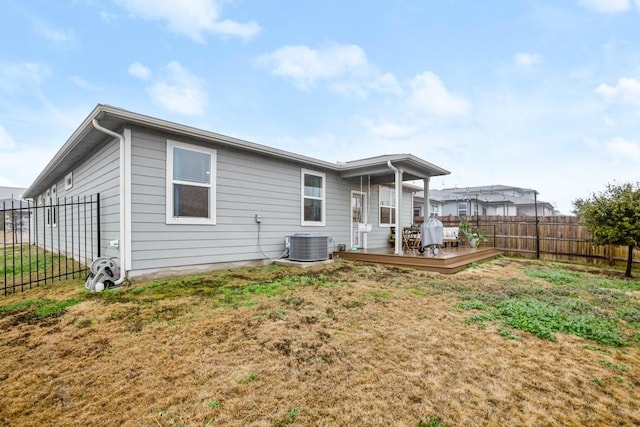 rear view of property featuring a wooden deck, central air condition unit, and a lawn