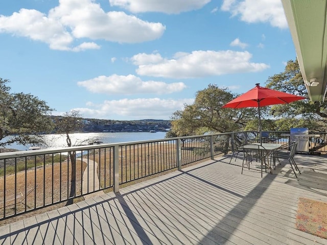 wooden deck featuring a water view and a grill