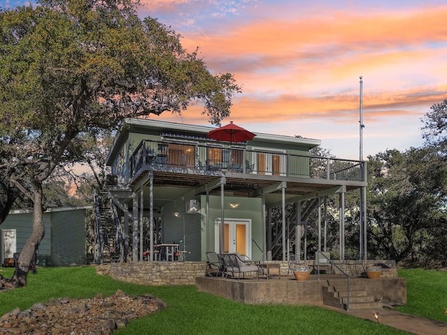 back house at dusk featuring a yard, a patio area, and a deck