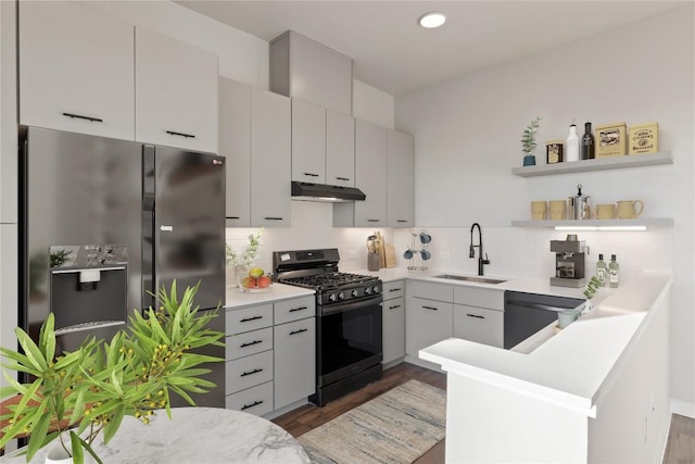 kitchen with dark wood-type flooring, sink, kitchen peninsula, decorative backsplash, and black appliances