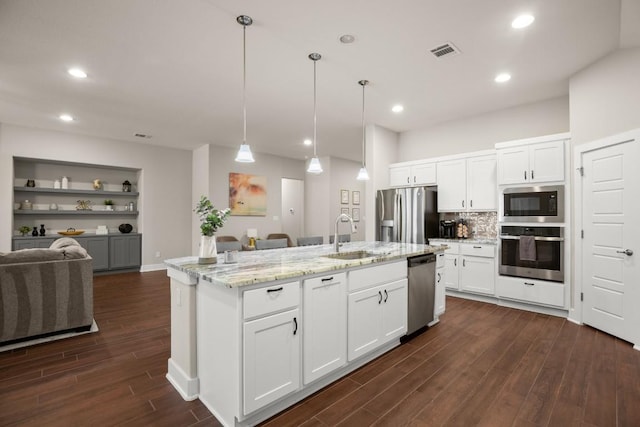 kitchen with stainless steel appliances, an island with sink, sink, and white cabinets