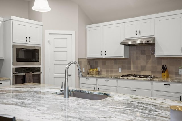 kitchen featuring tasteful backsplash, sink, white cabinets, and appliances with stainless steel finishes