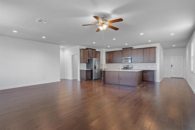 kitchen featuring appliances with stainless steel finishes, dark hardwood / wood-style flooring, a kitchen island, ceiling fan, and backsplash