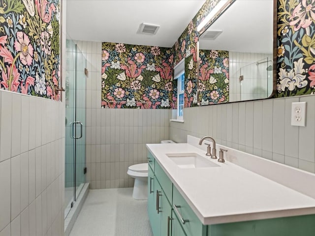 bathroom with tile walls, vanity, tile patterned floors, toilet, and walk in shower