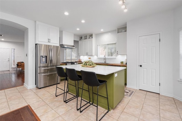 kitchen with a breakfast bar area, premium range hood, white cabinetry, appliances with stainless steel finishes, and a center island