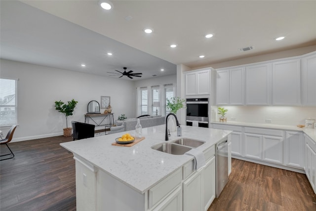 kitchen with dark wood-type flooring, sink, appliances with stainless steel finishes, an island with sink, and white cabinets