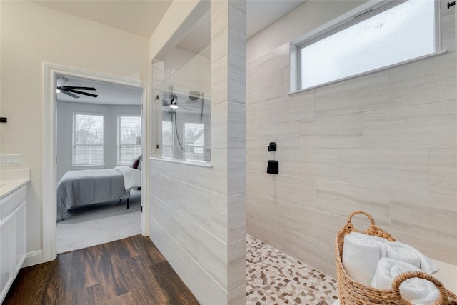 bathroom with vanity, hardwood / wood-style flooring, a healthy amount of sunlight, and tiled shower