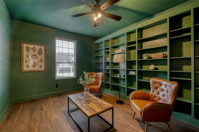 living area featuring wood-type flooring, ceiling fan, and a textured ceiling