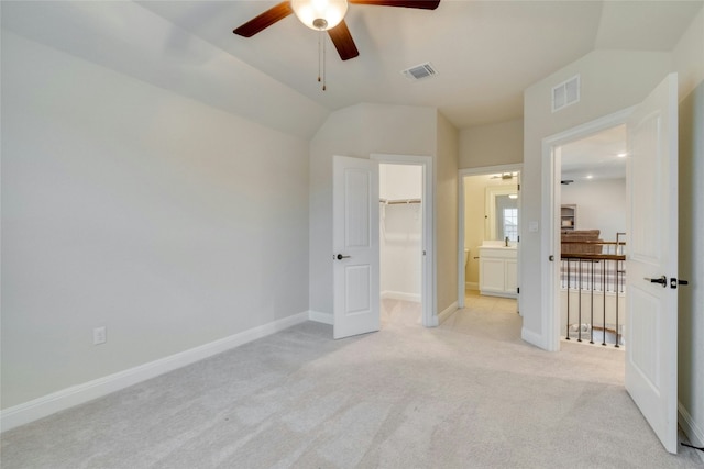 unfurnished bedroom featuring ceiling fan, a closet, a spacious closet, and light carpet