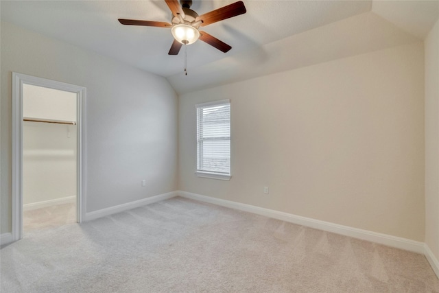 unfurnished bedroom with light colored carpet, lofted ceiling, a closet, and a walk in closet