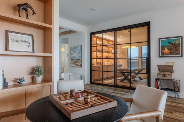 living area with wood-type flooring and built in shelves