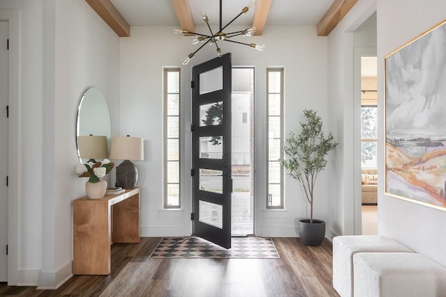 foyer with dark hardwood / wood-style flooring, a chandelier, and beamed ceiling