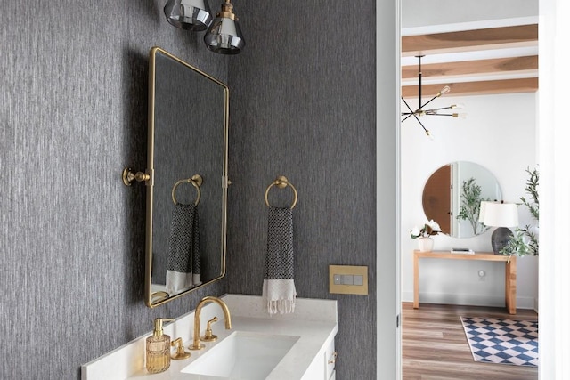 bathroom featuring beamed ceiling, vanity, hardwood / wood-style floors, and a notable chandelier