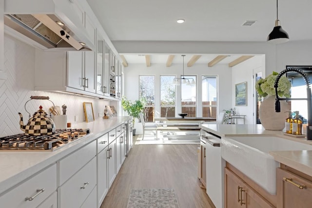 kitchen featuring white cabinetry, stainless steel gas cooktop, wall chimney exhaust hood, and decorative light fixtures