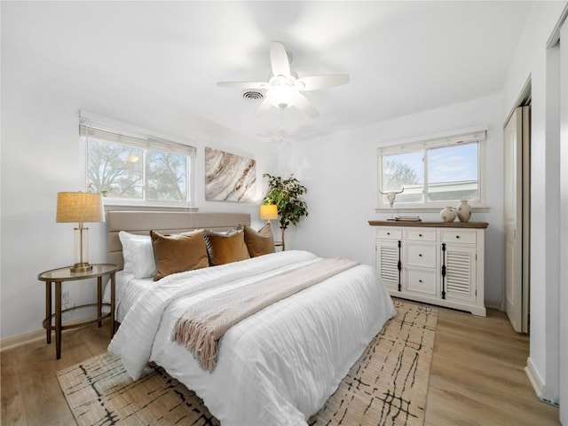 bedroom with multiple windows, light hardwood / wood-style floors, and ceiling fan