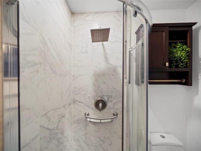 bathroom with a tile shower and toilet