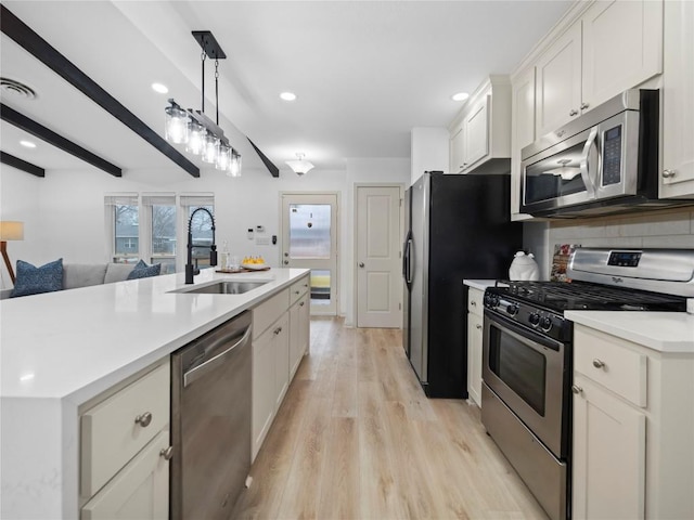 kitchen with sink, light hardwood / wood-style flooring, stainless steel appliances, white cabinets, and decorative light fixtures