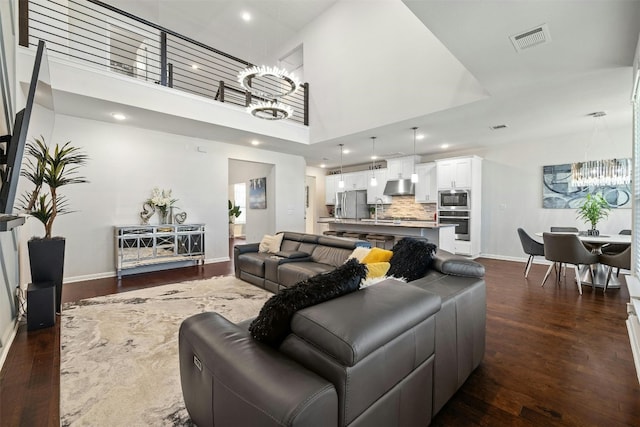 living room with a notable chandelier, dark wood-type flooring, sink, and a high ceiling