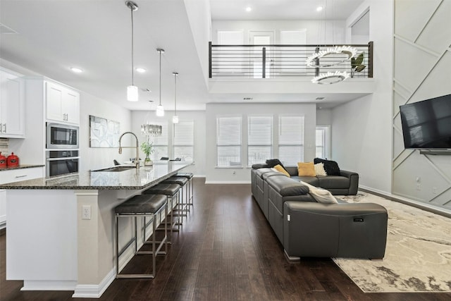 living room with a towering ceiling, dark hardwood / wood-style flooring, and sink