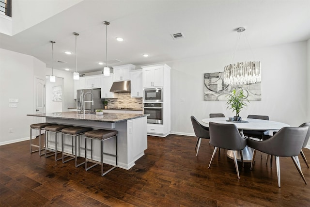 kitchen with sink, pendant lighting, stainless steel appliances, a kitchen island with sink, and white cabinets