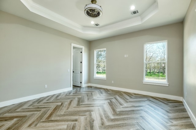 unfurnished room with crown molding, a raised ceiling, and light parquet floors